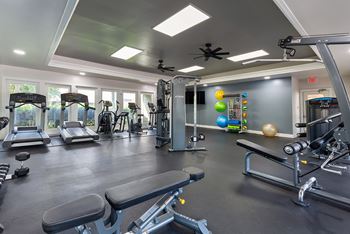 A gym with a variety of equipment including treadmills, weights, and exercise machines.